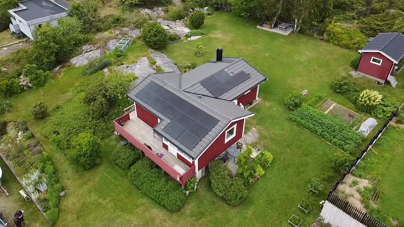 Rött hus med helsvarta solpaneler, drönarbild